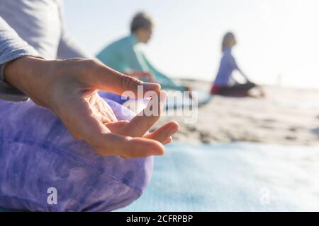 Mittlerer Teil der Frau, die am Strand Yoga praktiziert Stockfoto