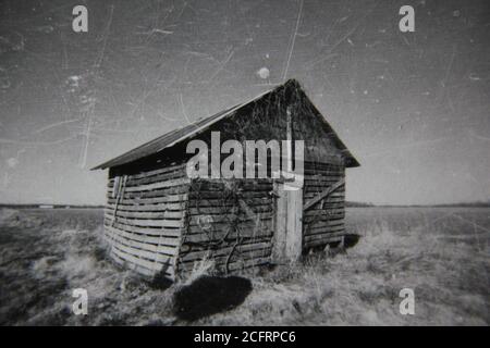 Feine 70er Jahre Vintage Schwarz-Weiß-Fotografie einer alten verwitterten und zerschlagene Hütte, die auf den Feldern steht. Stockfoto
