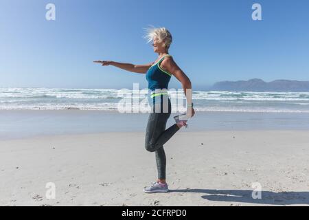 Ältere Frau praktizieren Yoga am Strand Stockfoto