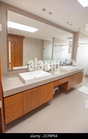 Badezimmer mit zwei Waschbecken und Wasserhähnen, vor einem großen Spiegel, elegantes modernes Design Stockfoto
