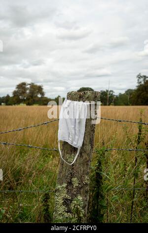 Abgeworfene covid 19 Gesichtsmaske auf einem Zaunpfosten Stockfoto