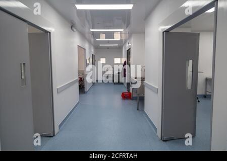 Korridor mit mehreren Türen, weißen Wänden, Waschbecken und Lampen mit blauem Boden Stockfoto