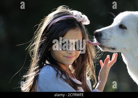 Junges Mädchen mit ihrem weißen und freundlichen Welpen Hund küssen Sie Stockfoto