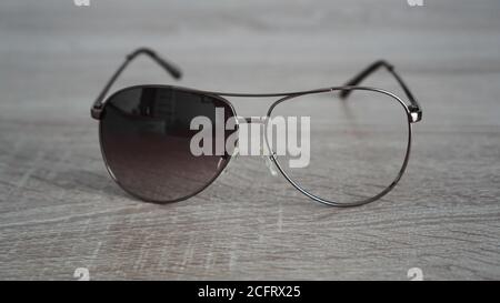 Gebrochene Sonnenbrille ohne Glas auf grauem Holzhintergrund Stockfoto