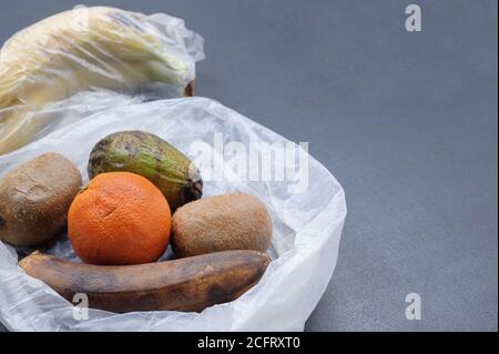 Verdorbene Früchte in der Plastiktüte auf dem grauen Hintergrund. Müllhalde verfaulte Lebensmittel. Zero Waste Konzept. Bild mit Kopierbereich, horizontal. Stockfoto