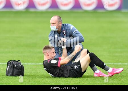 Ash Hunter (10) von Salford City erhält Behandlung auf dem Pitch nach einer Verletzung Stockfoto