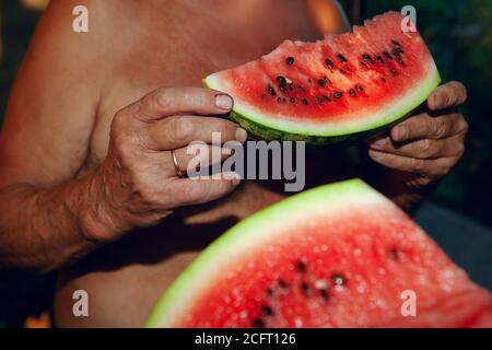 Mann, der Wassermelone isst. Bauer hält Wassermelone im hans bereit zu essen Stockfoto
