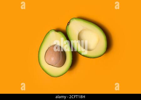 Zwei Hälften reifer Avocado auf orangefarbenem Hintergrund Stockfoto