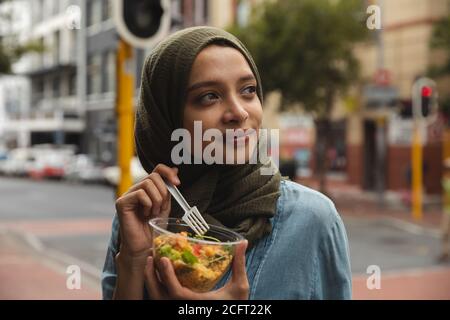 Frau in Hijab nimmt Snack auf der Straße Stockfoto