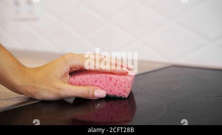 Weibliche Hand waschen Elektro-Kochfeld in der modernen Küche Stockfoto