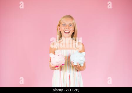 Überrascht schöne blonde Mädchen zeigt zwei Sparschweine Stockfoto