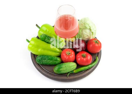 Ein Glas frisch gepresster Gemüsesaft und frisches Gemüse auf einem runden Tablett auf weißem Hintergrund. Stockfoto