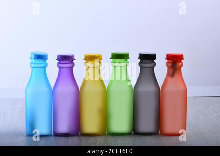 Reihe von bunten alkoholfreien Getränken auf grauem Hintergrund. Energy Drinks Behälter mit verschiedenen Geschmacksrichtungen auf Holztisch. Farbauswahl und Behälterkonzept. Set von Flaschen in verschiedenen Farben. Stockfoto