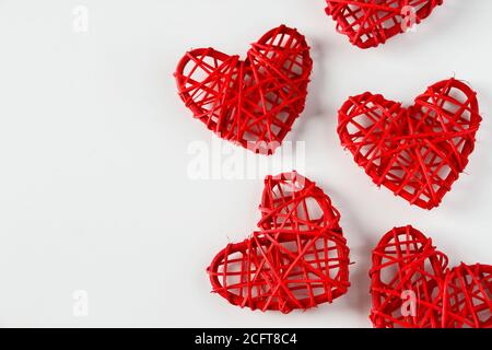 Rote handgefertigte Herzen aus Zweigen auf weißem Hintergrund. Viele rote Herzen aus Weinbauzweigen auf weißem Hintergrund. Hintergrund von Herzen für desi Stockfoto