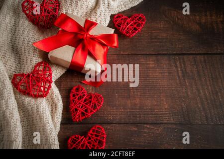 Valentinstag Geschenk in einer Box mit einem roten Band auf einem braunen Hintergrund. Geschenkbox aus Bastelpapier mit rotem Band zum Valentinstag. Handgefertigte Herzen Stockfoto