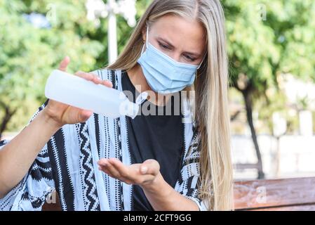 Junge kaukasische blonde Frau, die ihre Hände mit hydroalkoholischem Gel reinigt Stockfoto