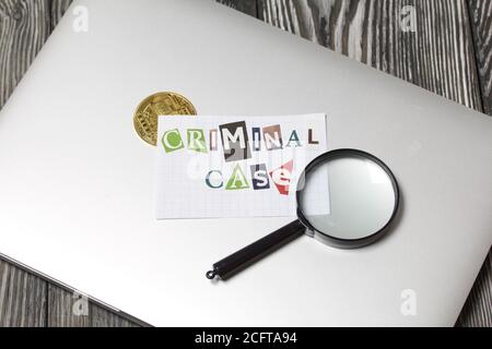 Die Phrase Criminal Case aus Buchstaben aus einer Zeitschrift geschnitten und auf einem Blatt Papier geklebt. Das Blatt mit der Aufschrift liegt auf dem Laptop-Cover. Stockfoto