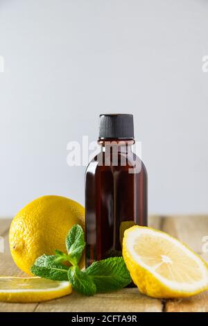 Kosmetik für Spa-Therapie. Flasche aromatisches Öl mit Zitrone und Minze auf Holzgrund. Stockfoto