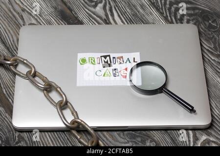 Die Phrase Criminal Case aus Buchstaben aus einer Zeitschrift geschnitten und auf einem Blatt Papier geklebt. Das Blatt mit der Aufschrift liegt auf dem Laptop-Cover. Stockfoto