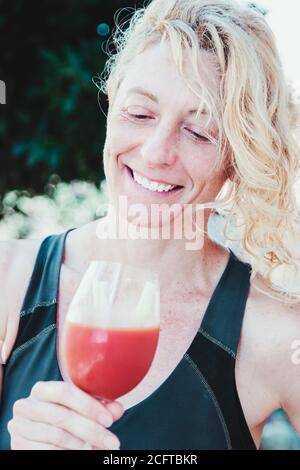 Junge reife blonde Frau in Sportswear Outdoor mit einem Glas Tomatensaft. Stockfoto