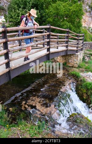 Frau mit Hut und Gesichtsmaske in Brücke und Fluss. Stockfoto