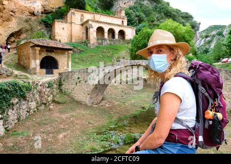 Wanderer reife junge Frau mit einer Gesichtsmaske in der Nähe einer alten Kapelle. Stockfoto