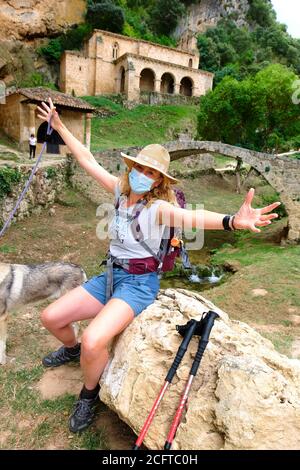 Wanderer reife junge Frau mit einer Gesichtsmaske in der Nähe einer alten Kapelle. Stockfoto