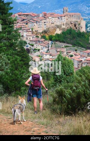 Wanderfrau mit Hut und Hund und Blick auf die Stadt. FRIAS-Stadt. Burgos Provinz. Kastilien und Leon, Spanien Stockfoto