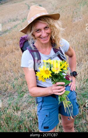 Reife junge Frau mit einem Sonnenblumenstrauß im Freien. Stockfoto