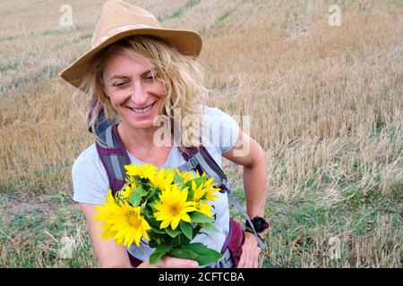 Reife junge Frau mit einem Sonnenblumenstrauß im Freien. Stockfoto