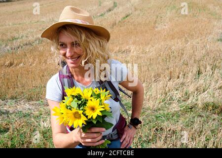 Reife junge Frau mit einem Sonnenblumenstrauß im Freien. Stockfoto