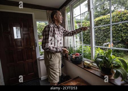 Ältere Paar saß in ihrer Veranda soziale Distanzierung zu Hause während der Coronavirus Pandemie Lockdown, Wales, Vereinigtes Königreich Stockfoto