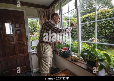 Ältere Paar saß in ihrer Veranda soziale Distanzierung zu Hause während der Coronavirus Pandemie Lockdown, Wales, Vereinigtes Königreich Stockfoto