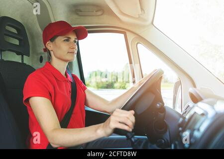 Transport-Dienstleistungen - junge Frau in roten Uniform fahren van Stockfoto