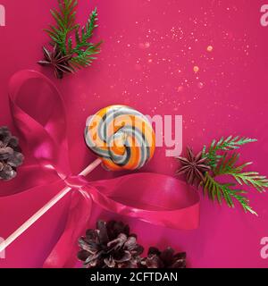 Weihnachtsbonbon auf einem rosa Hintergrund, wie ein Zauberstab. Komposition mit Platz für Text. Stockfoto