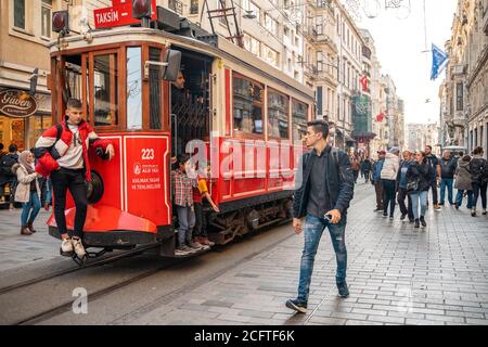 23.10.2019 Istanbul, Türkei. Vintage rote Straßenbahn fährt entlang der Straße von Istanbul. Im Hintergrund laufen die Leute zur Bushaltestelle. Das Konzept von tr Stockfoto