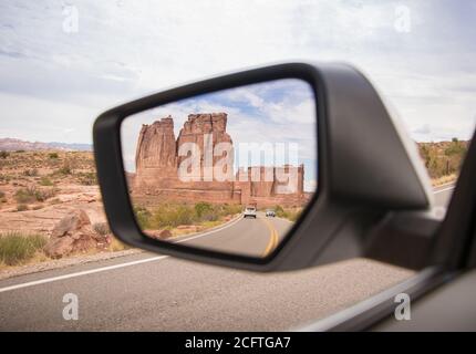 Ein Blick auf die 'Organ'-Felsformation im Rückansicht Spiegel eines Autos, das im Arches National Park fährt Stockfoto