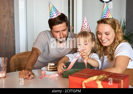 Glückliche Familie gratulieren Tochter Geburtstag in der Küche, geben sie Geschenke an sie, feiern. Familie zu Hause Stockfoto