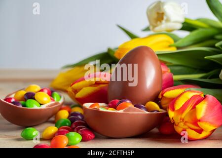 Helle bunte Tulpen und Schokolade Ostereier auf einem hölzernen Hintergrund. Festliches Design, Platz für Text. Stockfoto