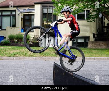 Ein kleiner Junge (8 Jahre alt) Einen großen Sprung auf seinem Mountainbike Stockfoto