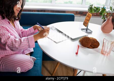 Glückliche schwangere Frau schriftlich in ihrem Schwangerschaftskalender, zu Hause. Ein Tagebuch zu halten, erwartet Baby Stockfoto