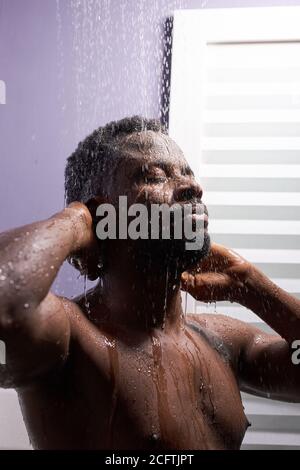 Schwarzer Mann Waschkopf mit Shampoo in der Dusche, genießen Sie das Bad am Morgen Stockfoto