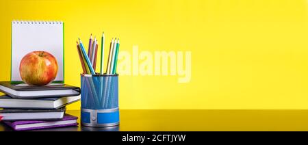 Zurück zur Schule Konzept. Schulbedarf und Bücher auf gelbem Hintergrund. Für Text platzieren. Bannerformat Stockfoto