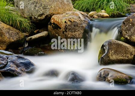 Zeitbezogene Exposition eines Wasserfalls zwischen nassen Felsen Stockfoto
