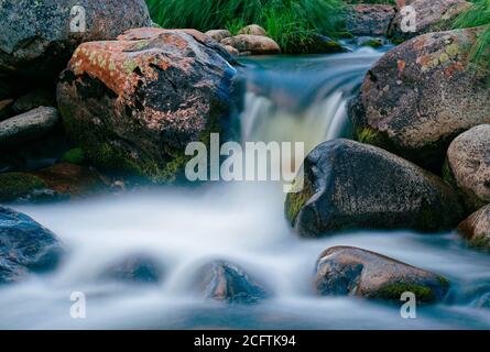 Zeitbezogene Exposition eines Wasserfalls zwischen nassen Felsen Stockfoto