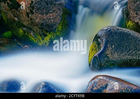 Zeitbezogene Exposition eines Wasserfalls zwischen nassen Felsen Stockfoto