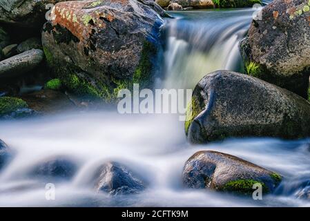 Zeitbezogene Exposition eines Wasserfalls zwischen nassen Felsen Stockfoto