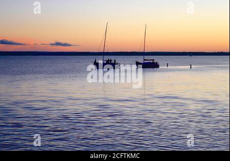 Zwei Segelboote bewegen sich langsam zurück zu ihrem Dock, während der Sonnenuntergang auf dem Ottawa River vergeht. Stockfoto