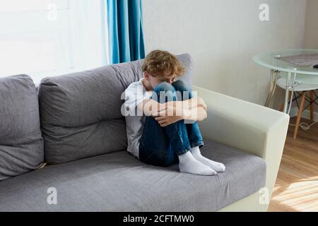 Trauriges Kind Junge sitzen weinend allein zu Hause. Schuljunge leiden unter Autismus Stockfoto