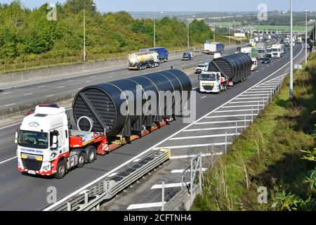 Breite Übergröße lange Zylinderform Last auf LKW niedrig Lader auf zwei Spuren der Autobahn M25 mit Begleitwagen Auf der Rückseite mit Stau Warteschlange UK Stockfoto